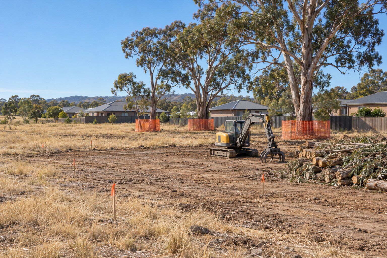 Land clearing, Bendigo: vacant bush block with a cleared house pad, cut logs beside a mini excavator and kept gums fenced off